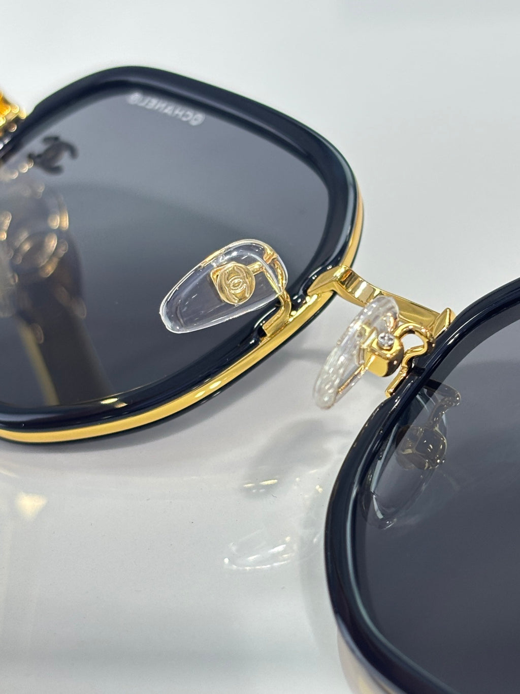 Chanel sunglasses close-up: dark round lenses with gold-tone rim and temple hardware