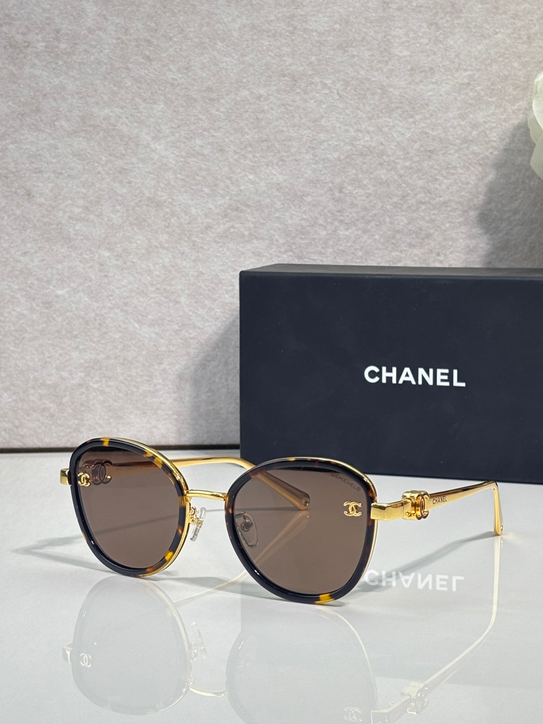 Round CHANEL sunglasses with dark lenses and tortoise-accented frame