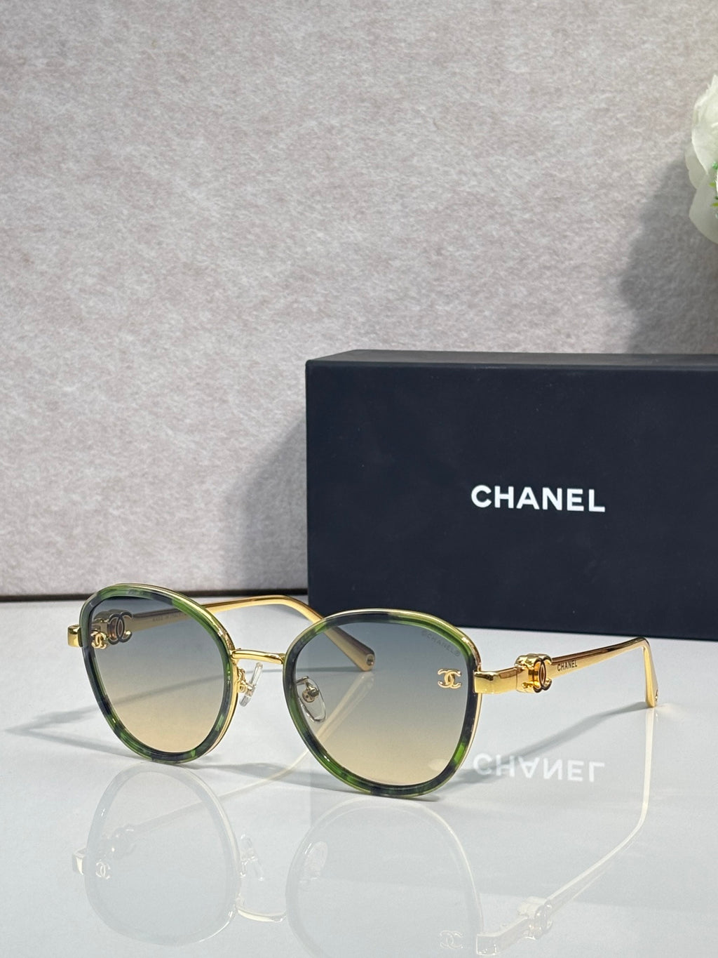 Round CHANEL sunglasses with green-tinted lenses and gold metal frame