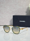 Round CHANEL sunglasses with green-tinted lenses and gold metal frame