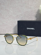 Round CHANEL sunglasses with green-tinted lenses and gold metal frame