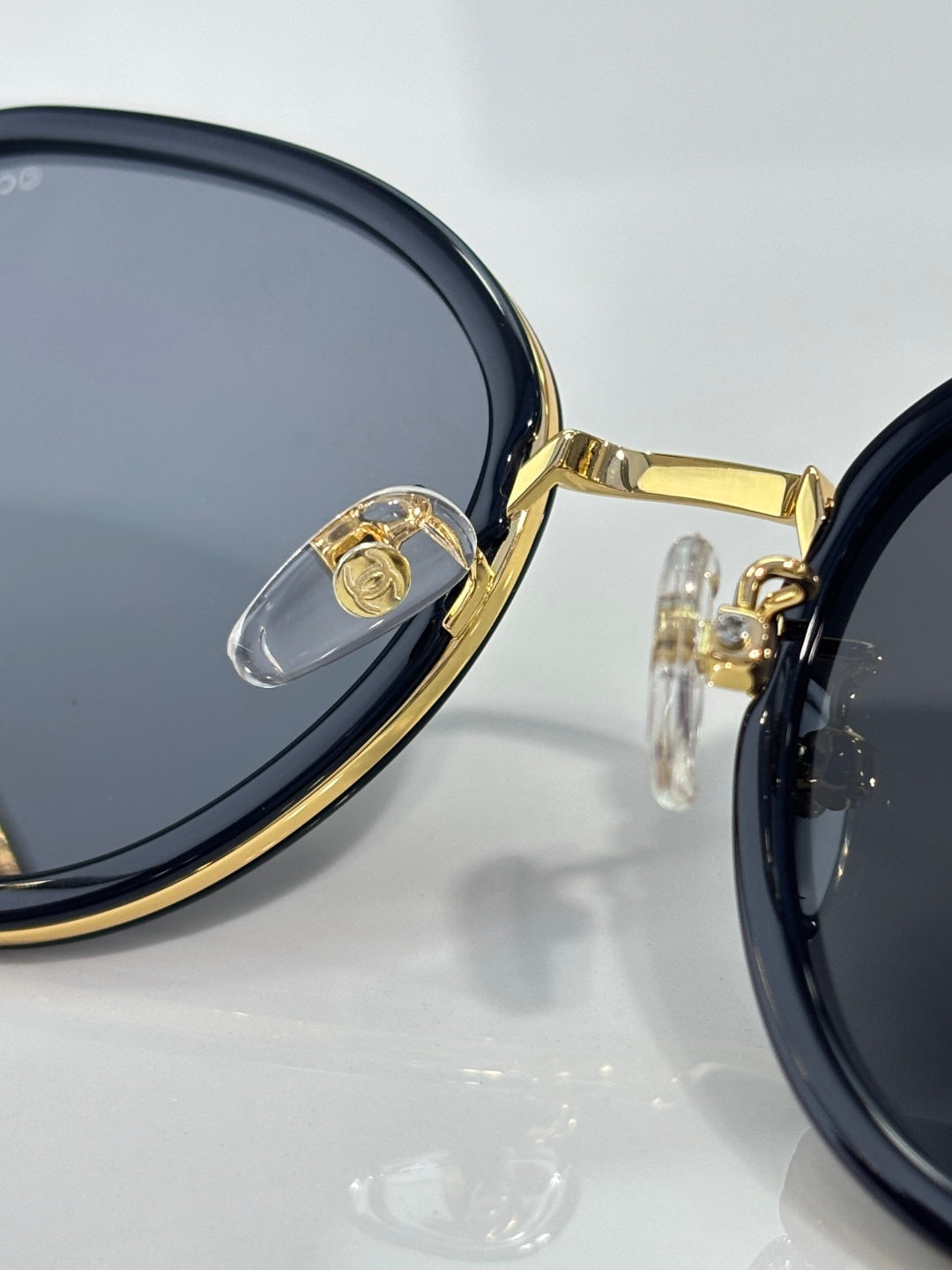 Close-up of CHANEL round sunglasses with dark lenses and gold rim