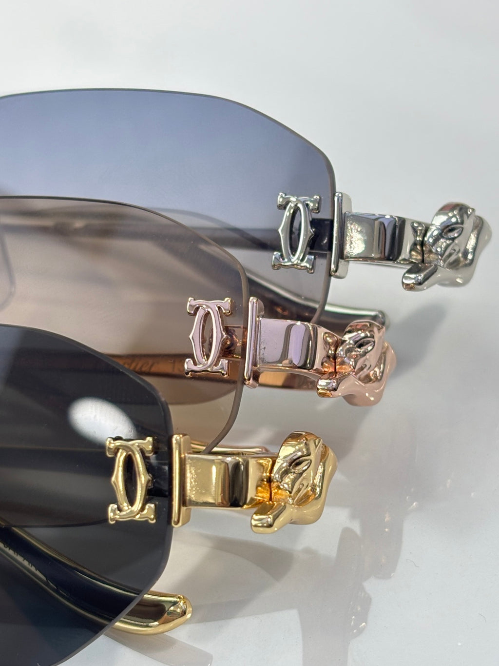 Close-up of sunglass hinges with engraved initials and mixed gold-silver hardware