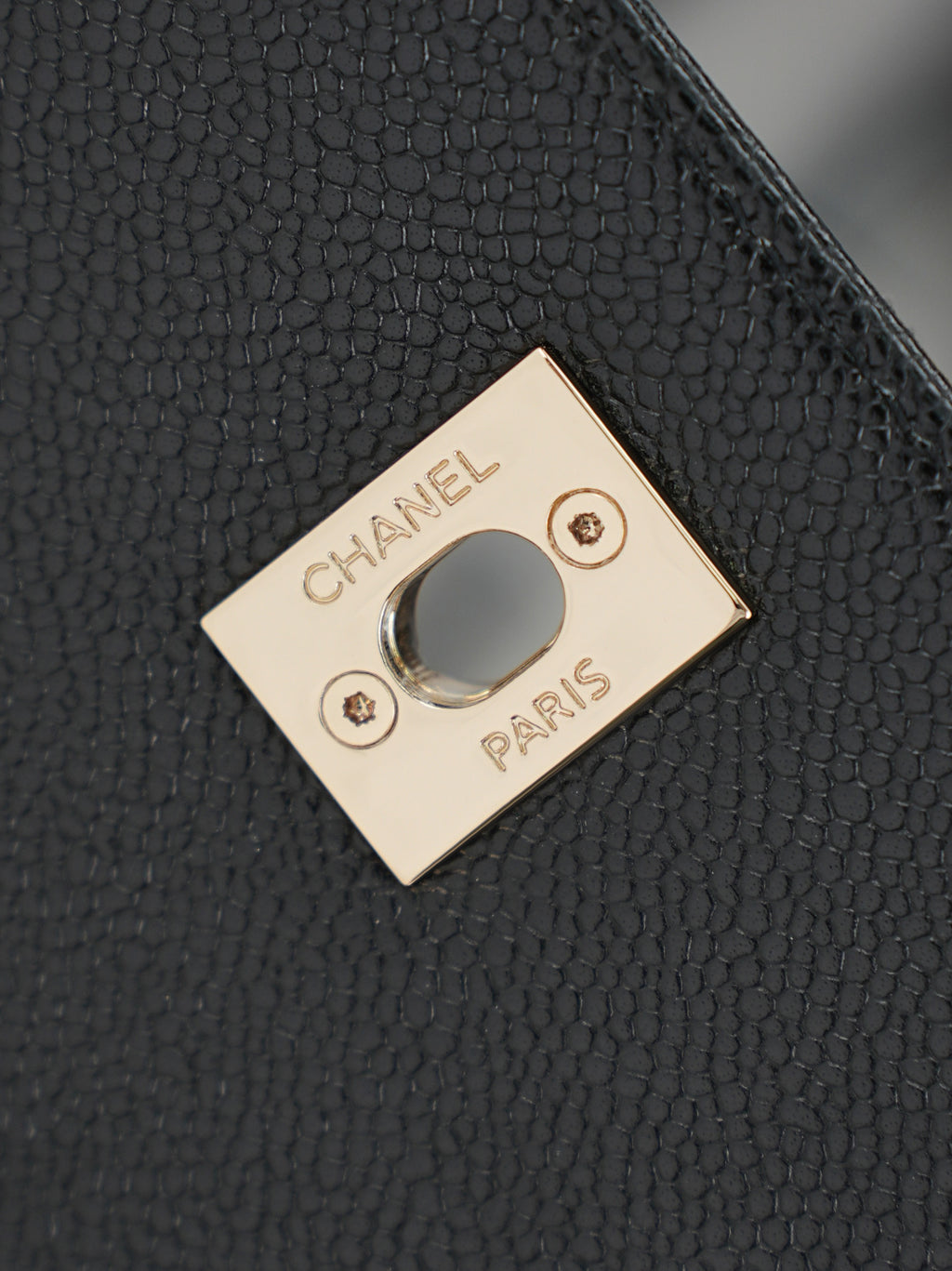 Chanel Paris logo tag on black grained leather bag with gold-tone frame
