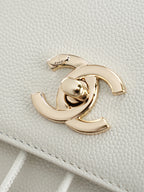 Gold-tone Chanel logo hardware on white textured leather bag flap