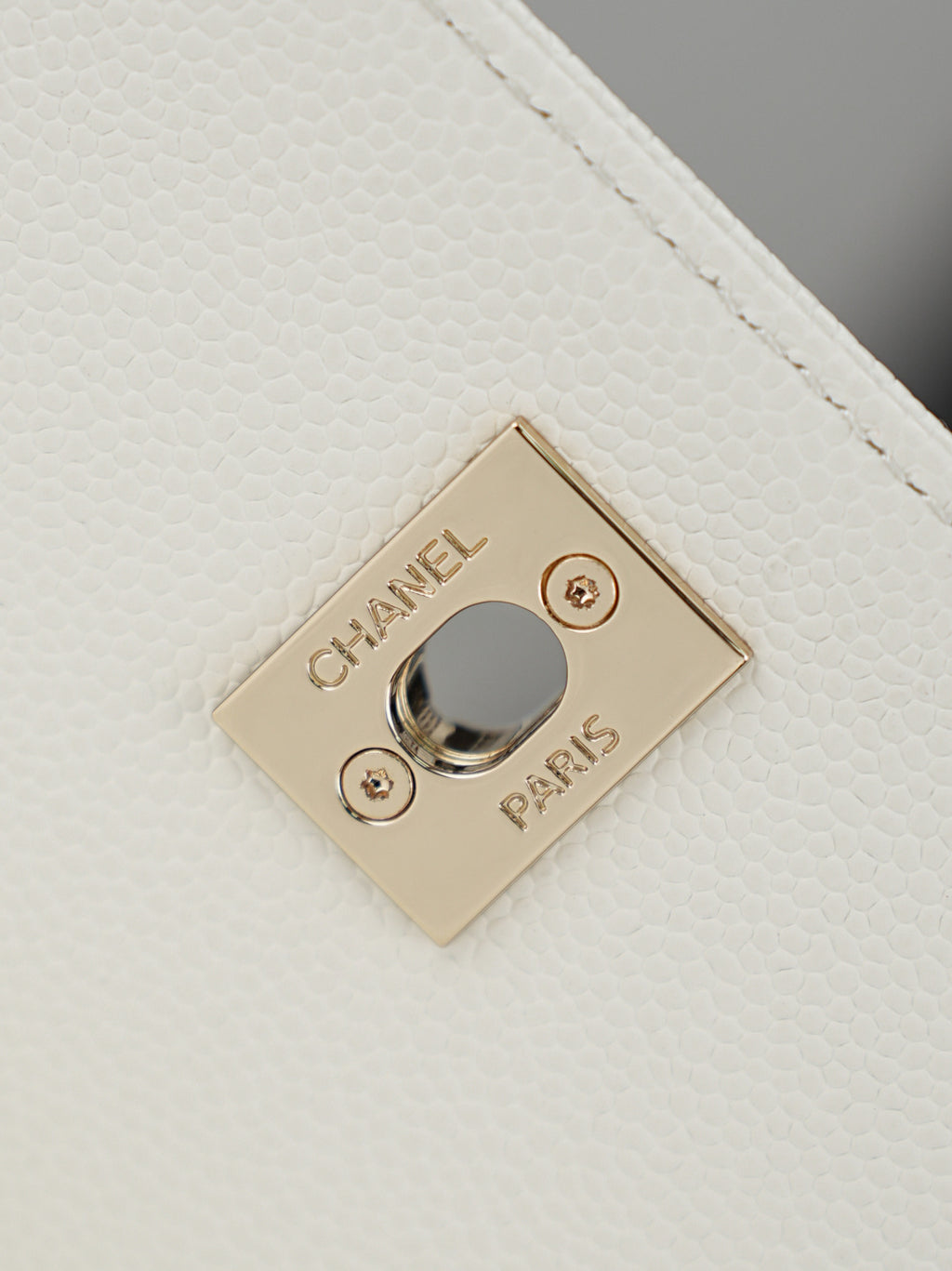 Gold Chanel Paris logo plate on white textured leather bag