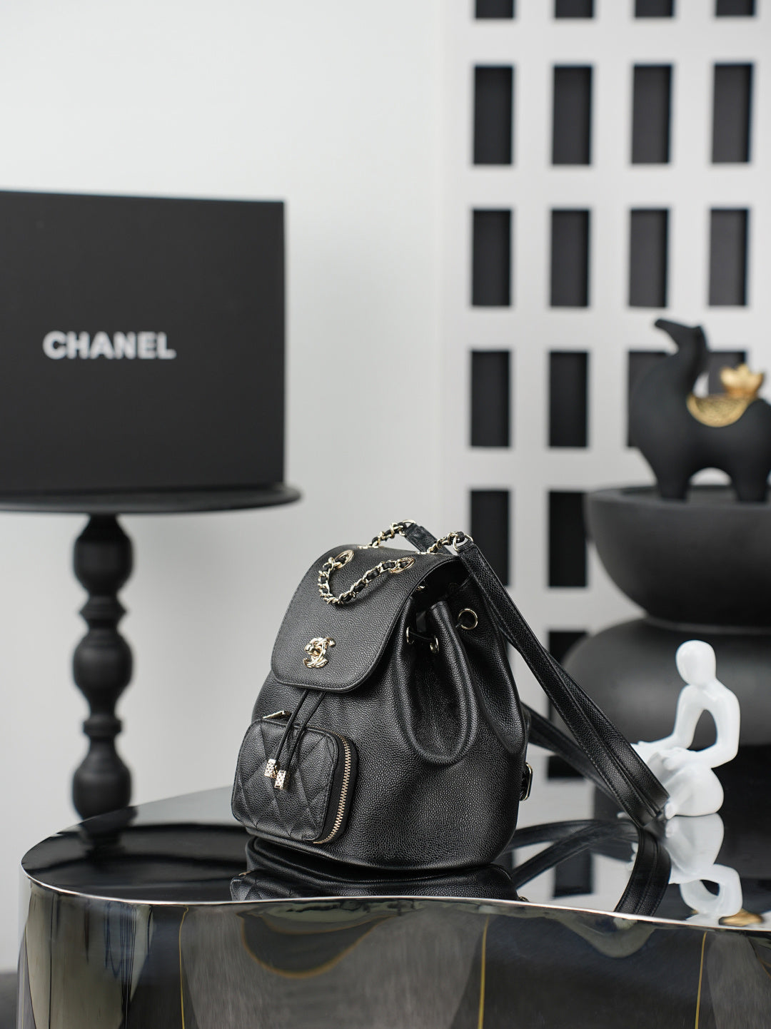 Chanel black bucket bag with chain strap, drawstring top, and front pockets