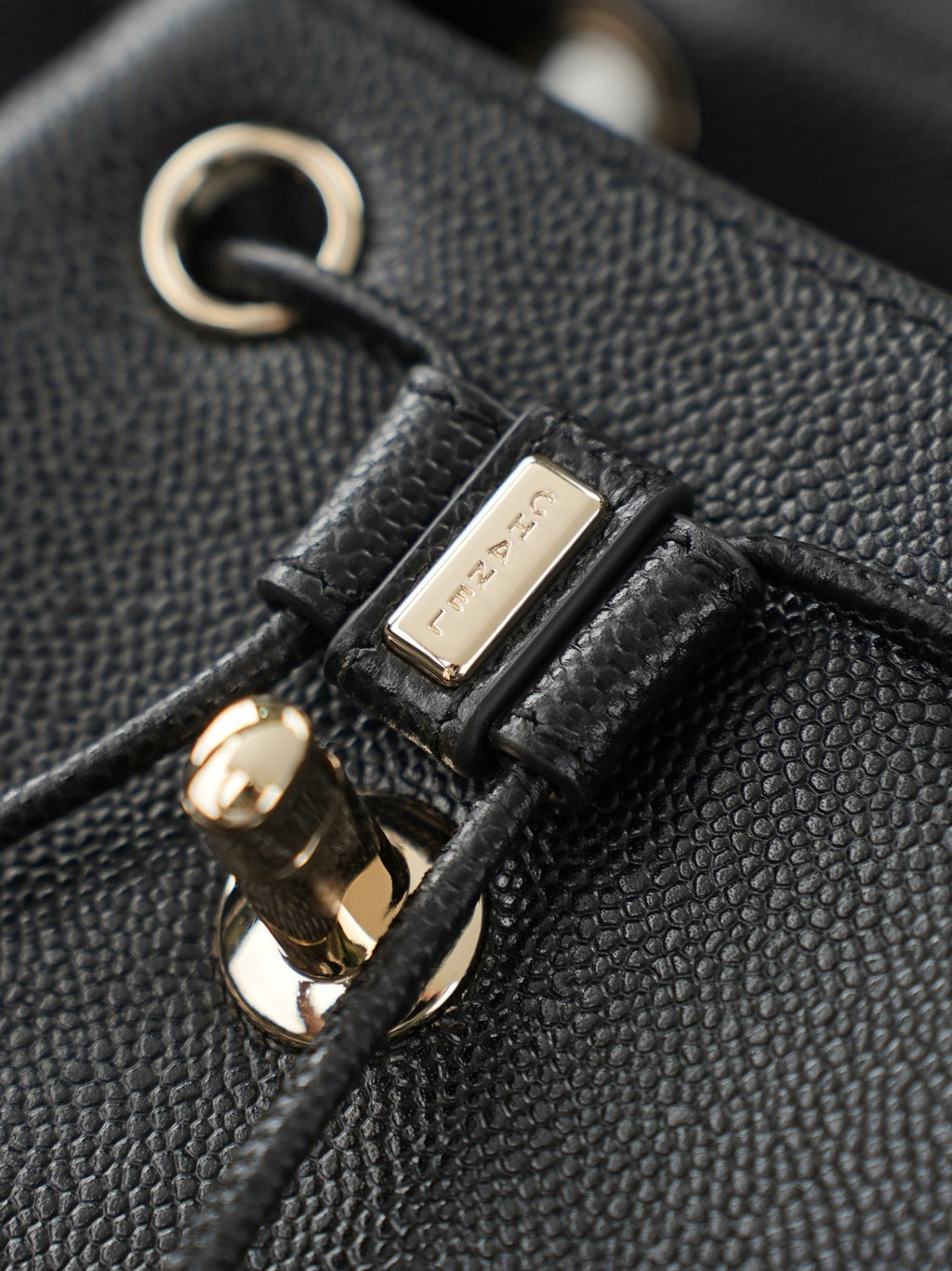 Chanel hardware close-up on black textured leather bag strap