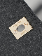 Chanel gold-tone plate logo detail on textured black leather bag