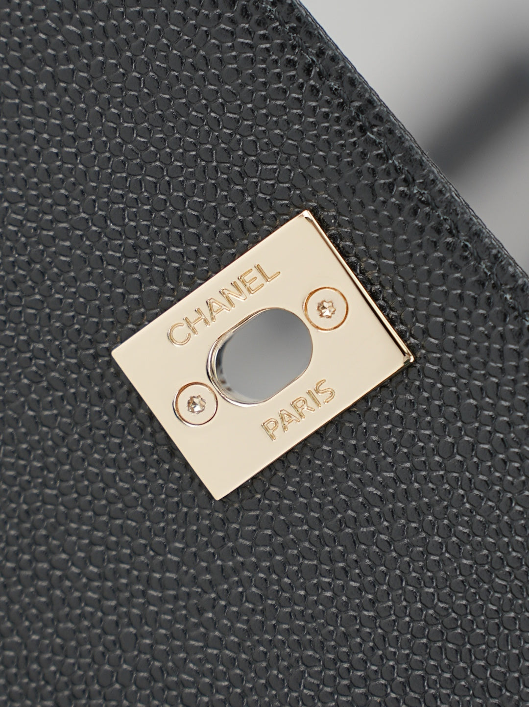 Chanel gold-tone plate logo detail on textured black leather bag