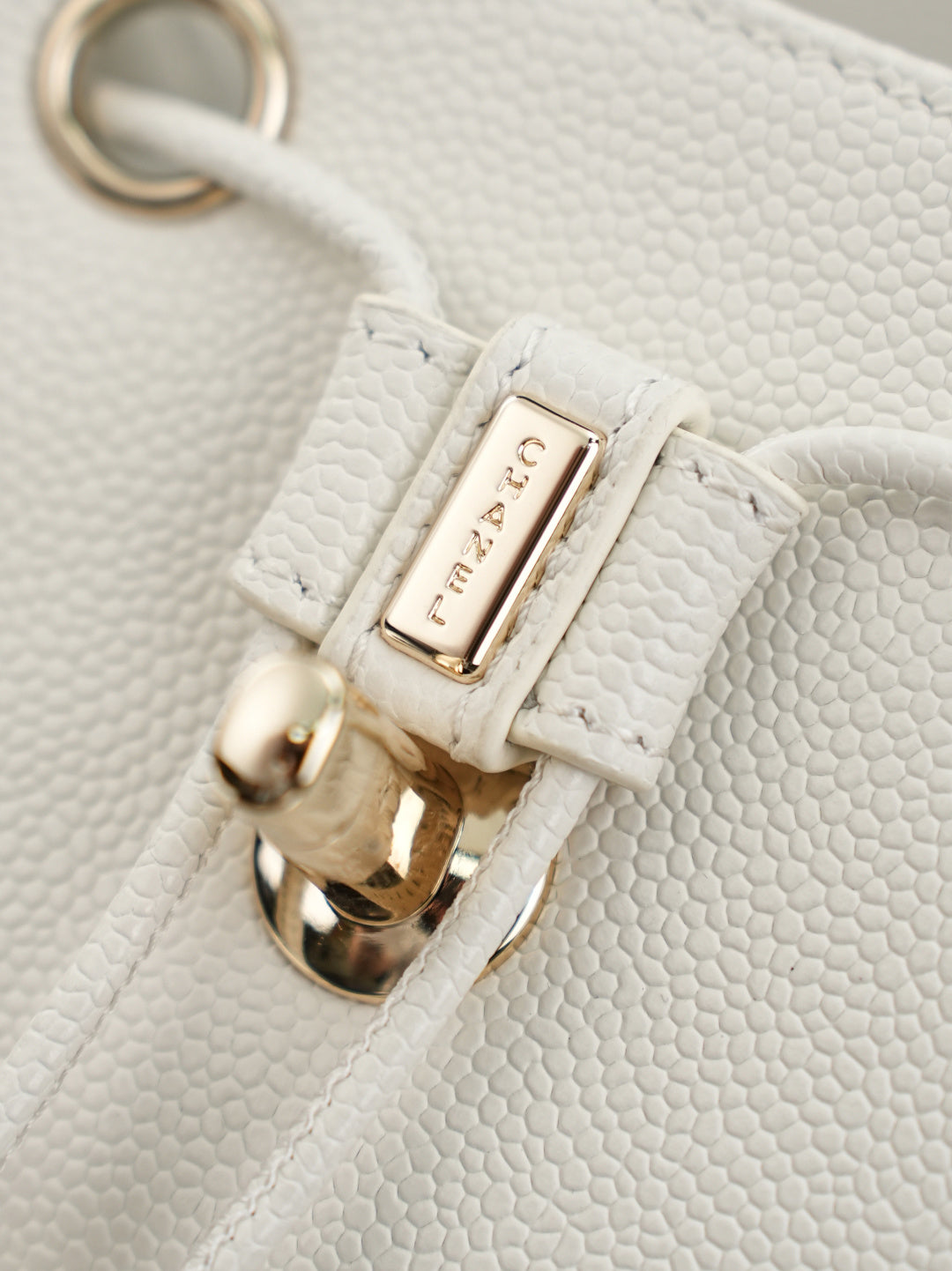 White bag detail with gold-tone ring clasp and logo label
