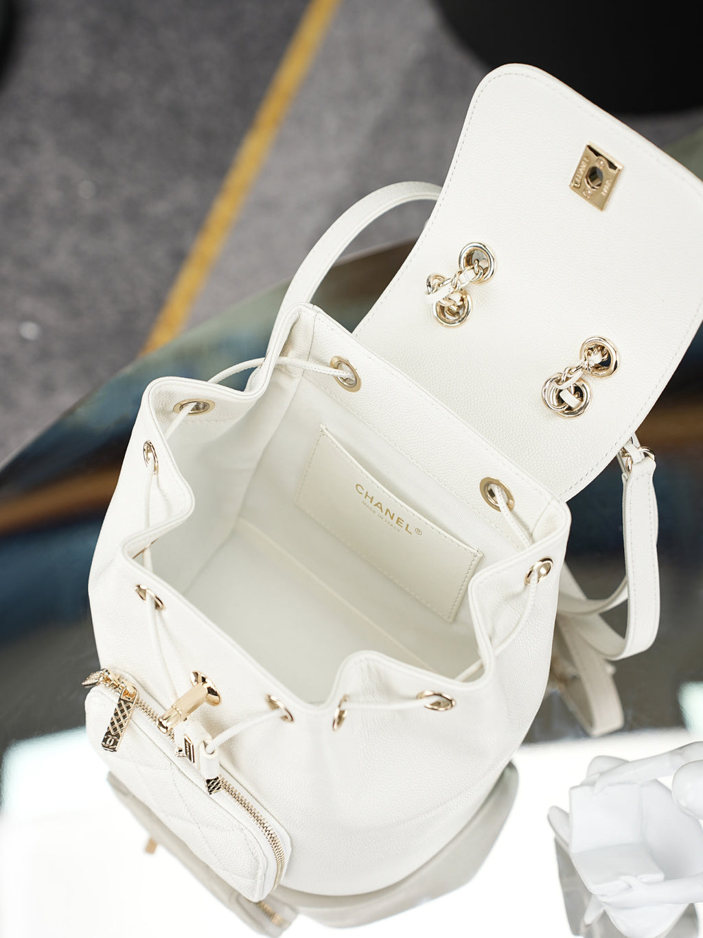 Open white bucket bag with gold hardware, chain strap, and interior pocket