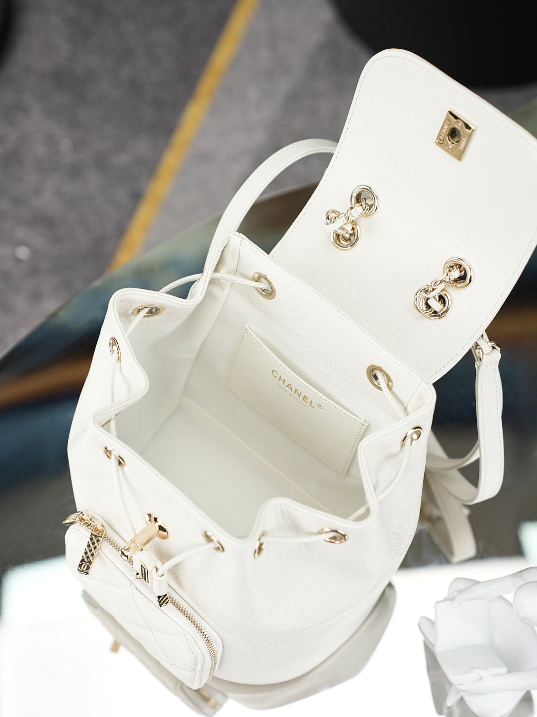 Open white bucket bag with gold hardware, chain strap, and interior pocket