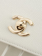 Close-up of gold-tone logo hardware on white quilted bag