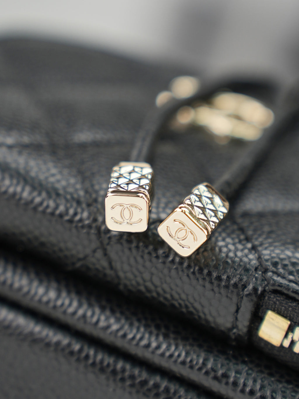 Chanel logo zipper pulls on dark leather with gold-tone hardware
