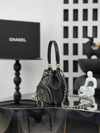 Chanel drawstring bucket bag in dark leather with side zip pocket and gold chain