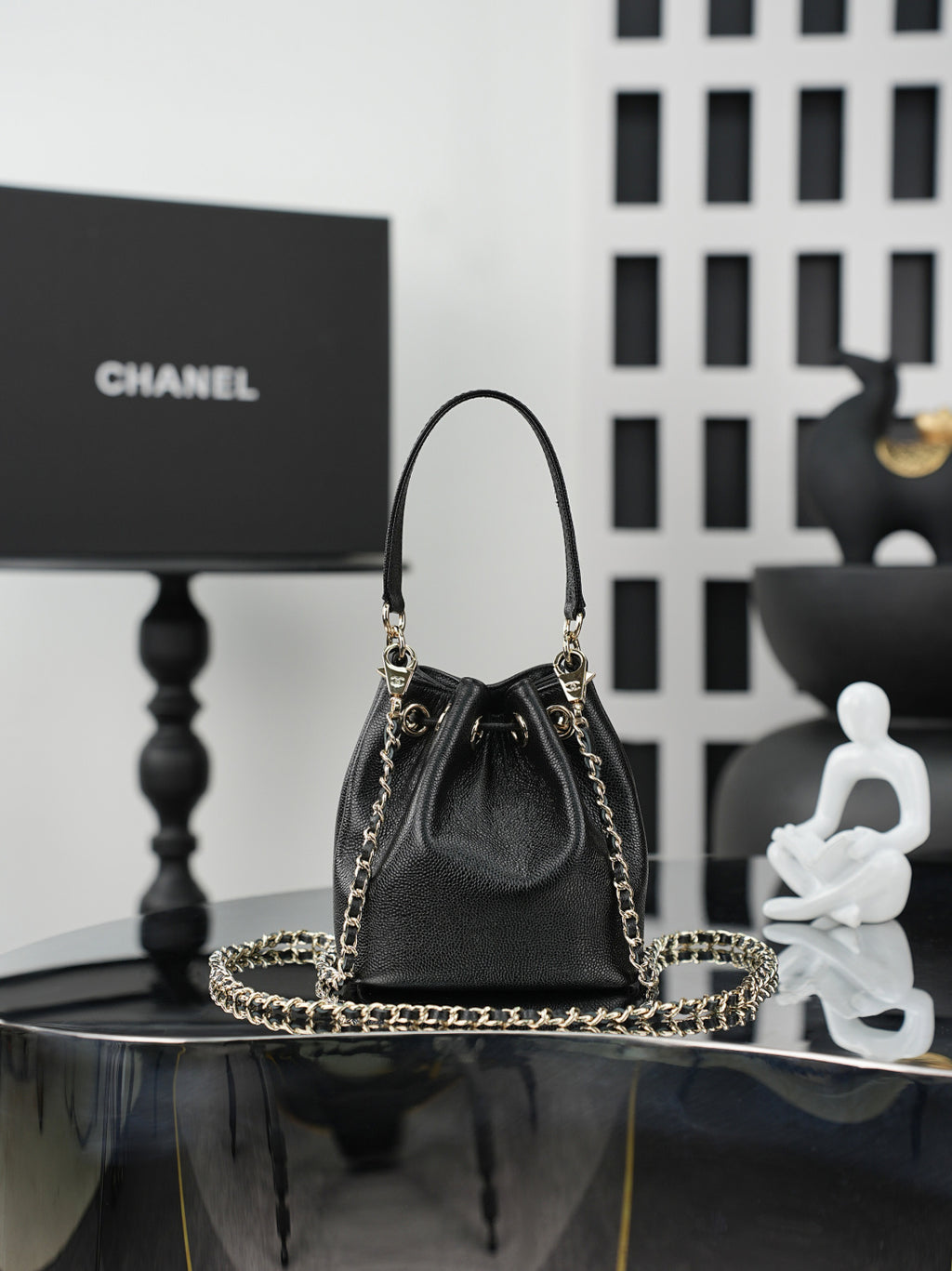 Chanel drawstring bag in dark leather with gold chain handles and centered CC detail