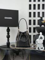 Chanel drawstring bag in dark leather with gold chain handles and centered CC detail