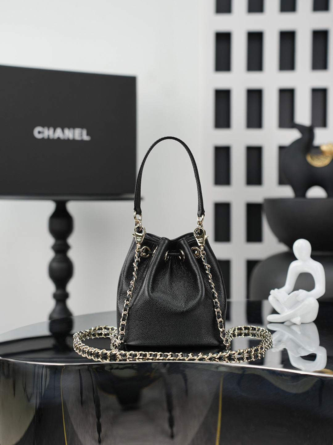 Chanel drawstring bag in dark leather with gold chain handles and centered CC detail