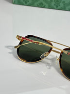 Sunglasses with green lenses and gold frame, red and green striped temple bar detail