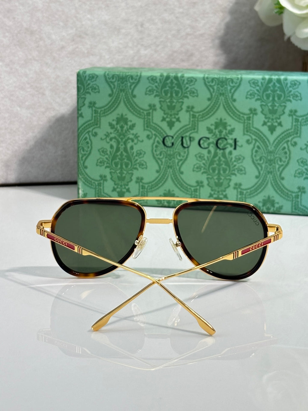 Gucci sunglasses front view with green lenses, gold frame, and tortoiseshell rim
