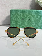 Gucci sunglasses front view with green lenses, gold frame, and tortoiseshell rim