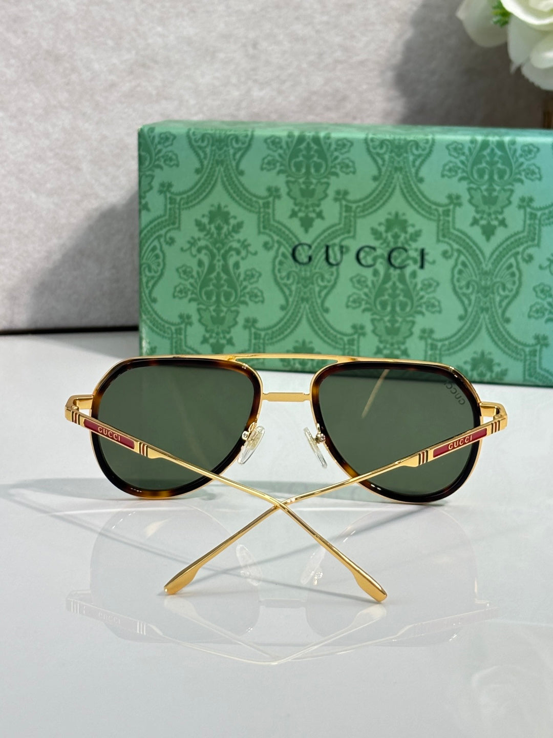 Gucci sunglasses front view with green lenses, gold frame, and tortoiseshell rim