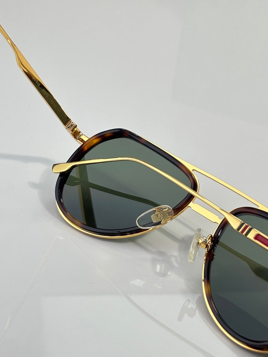 Gold-tone sunglasses with oval green lens and tortoiseshell rim, side profile