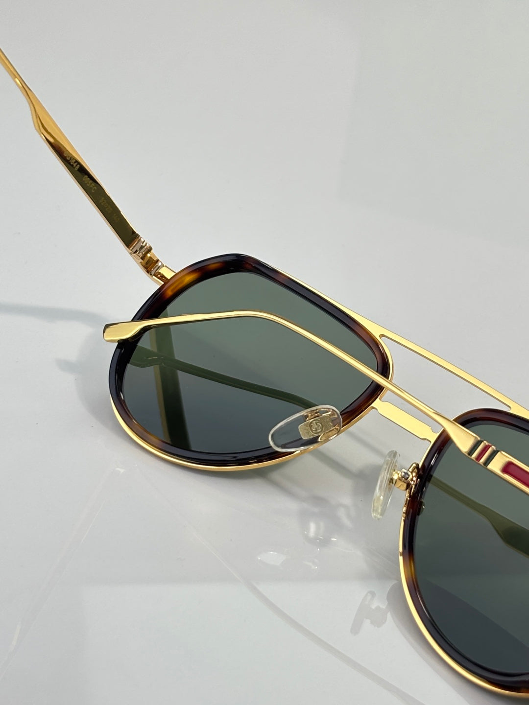 Gold-tone sunglasses with oval green lens and tortoiseshell rim, side profile