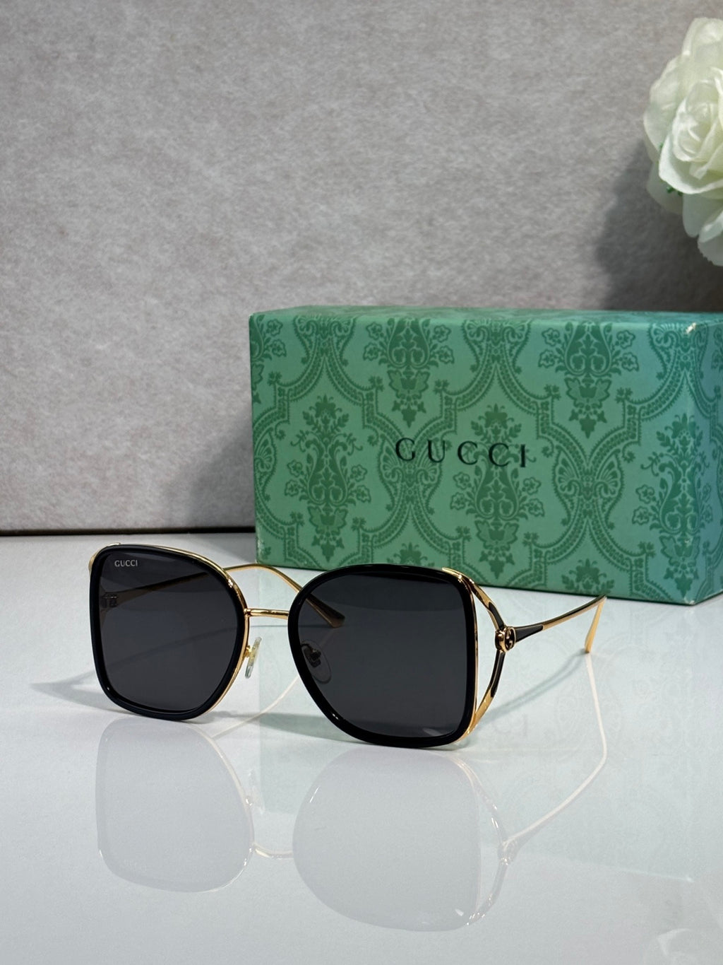 Black metal sunglasses with gold accents and dark tinted lenses, square rounded frames