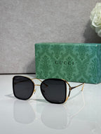 Black metal sunglasses with gold accents and dark tinted lenses, square rounded frames