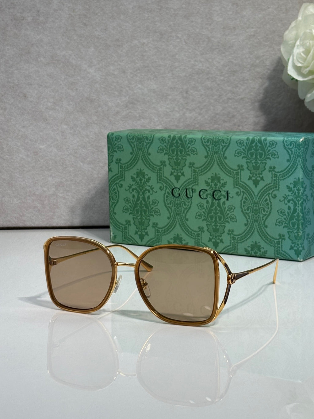 Gold and dark brown metal sunglasses with light tinted lenses and square rounded frames
