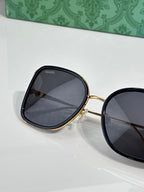 Oval sunglasses with dark lenses and gold-tone frame