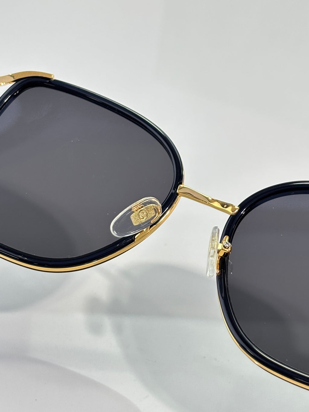 Close-up of oval sunglasses frame with gold-tone rim and dark lenses