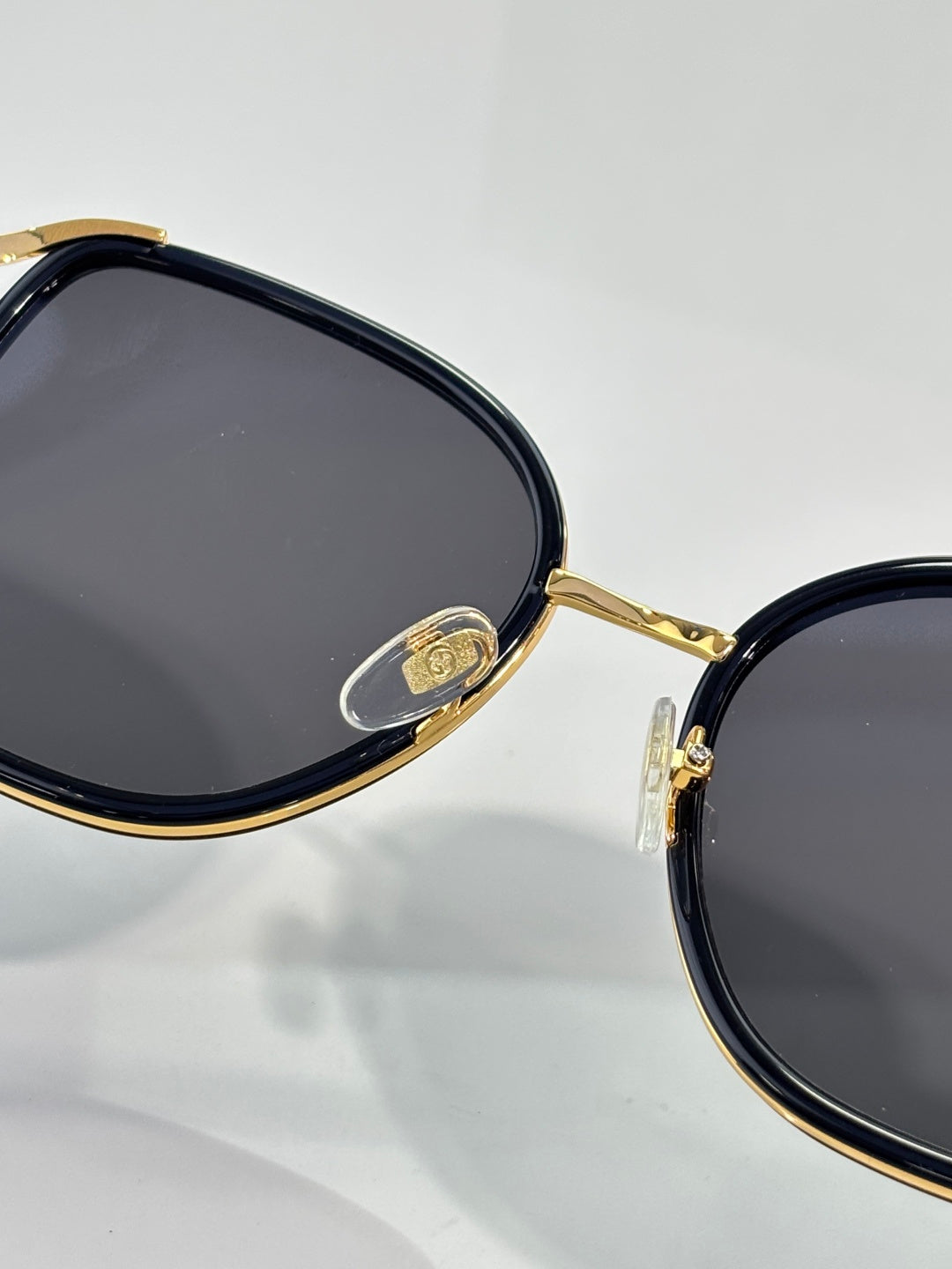 Close-up of oval sunglasses frame with gold-tone rim and dark lenses