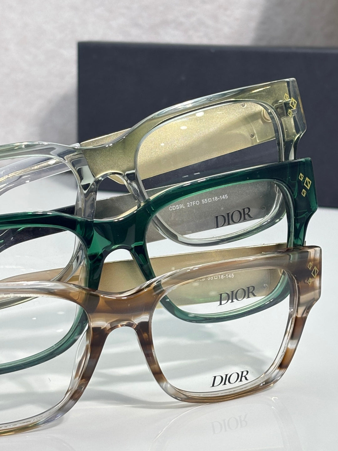 Dior eyeglasses close-up with layered frames in green, clear, and tan tones