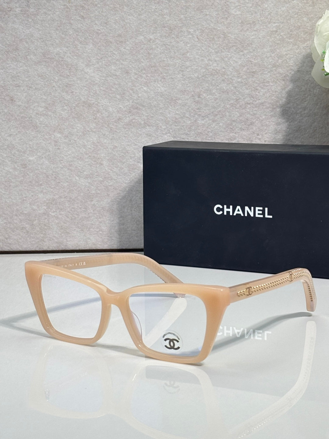 Chanel eyeglasses with light tan rectangular frame, clear lenses, gold logo on temple