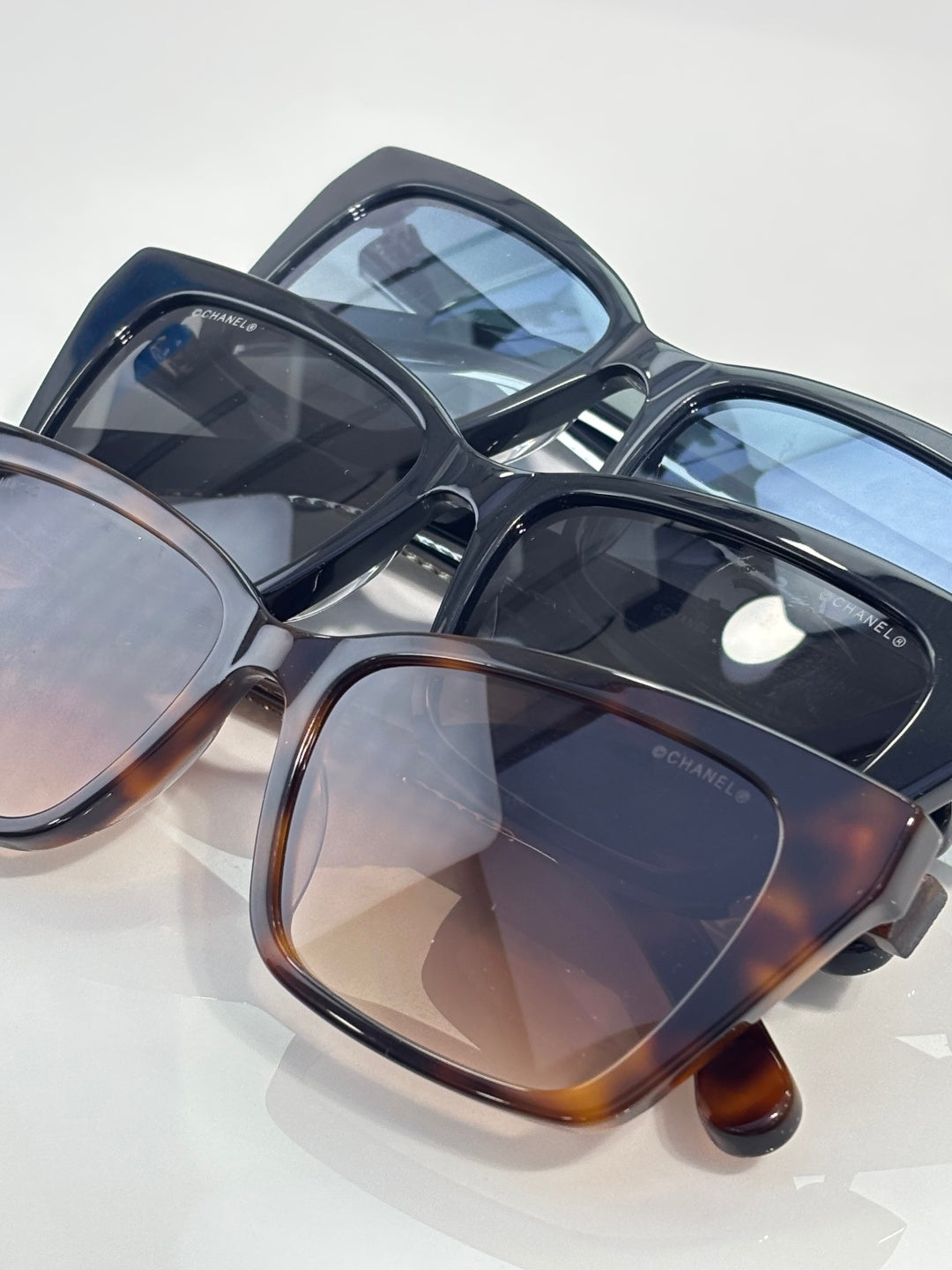 Chanel sunglasses with dark frames and blue-tinted lenses, glossy finish