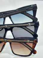 Chanel sunglasses close-up with gold chain-link accents on black and tortoiseshell temples