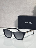 Chanel sunglasses with black acetate frame and dark gray lenses, gold logo accents