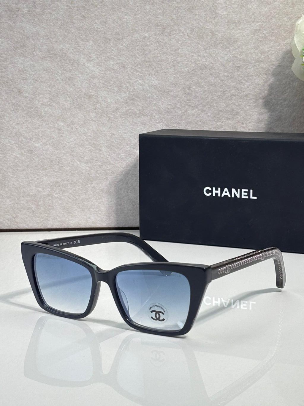 Chanel sunglasses with black acetate frame and blue-tinted lenses, gold temple details