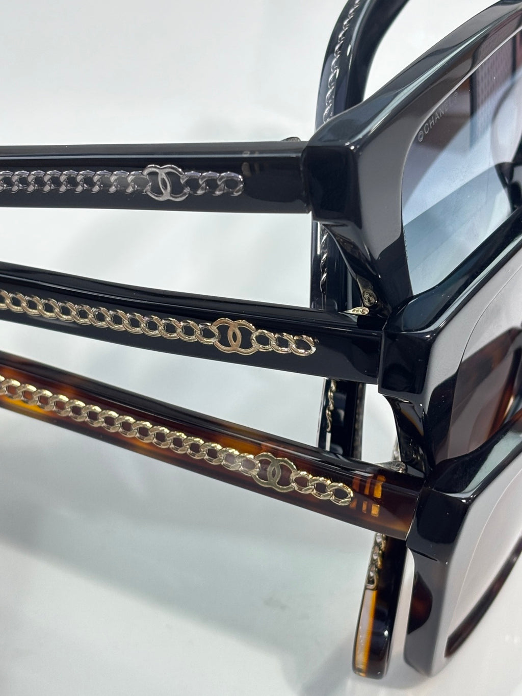 Chanel sunglasses close-up with black frames and gold chain-link temple detailing