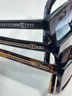 Chanel sunglasses close-up with black frames and gold chain-link temple detailing