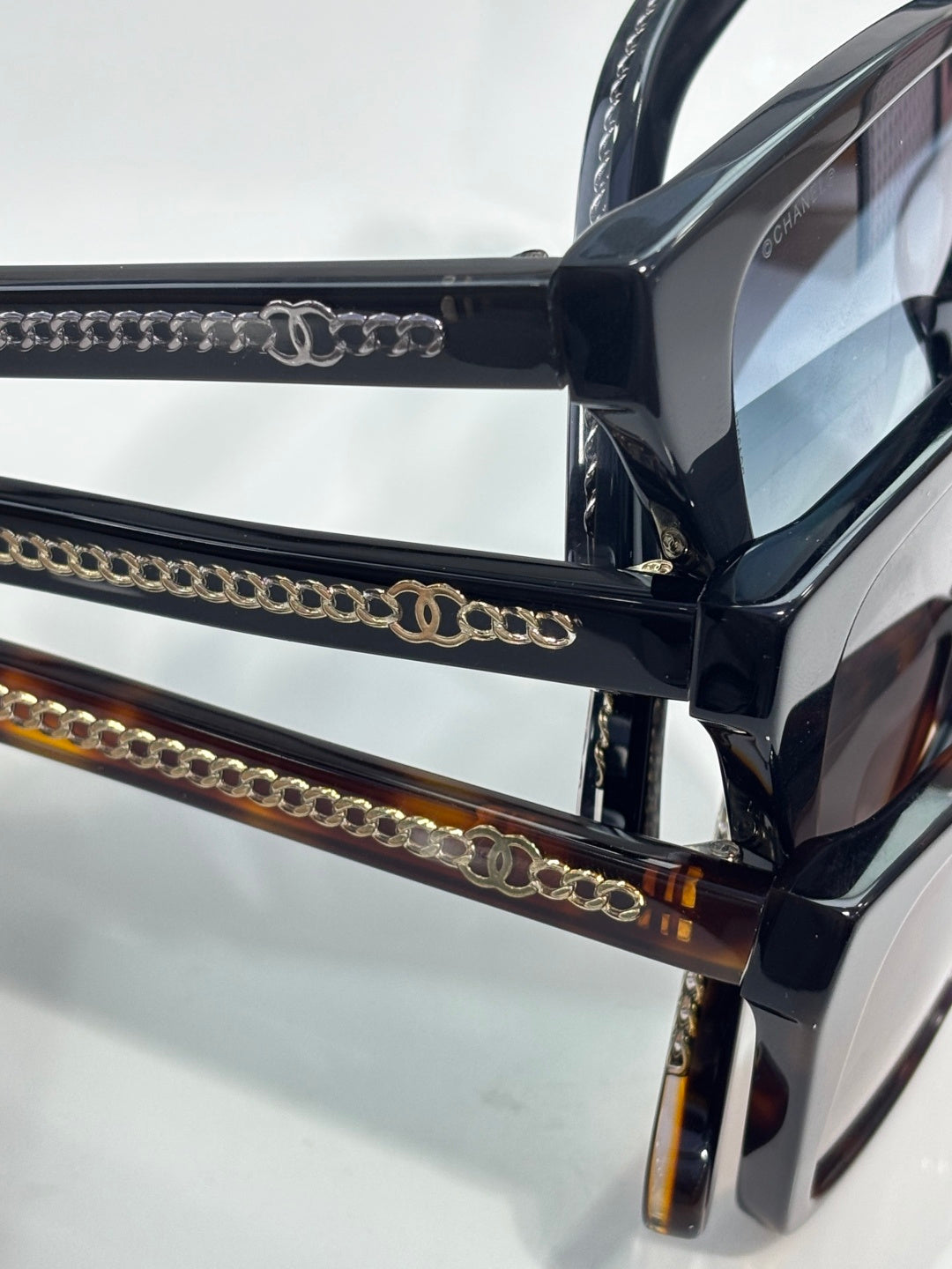 Chanel sunglasses close-up with black frames and gold chain-link temple detailing