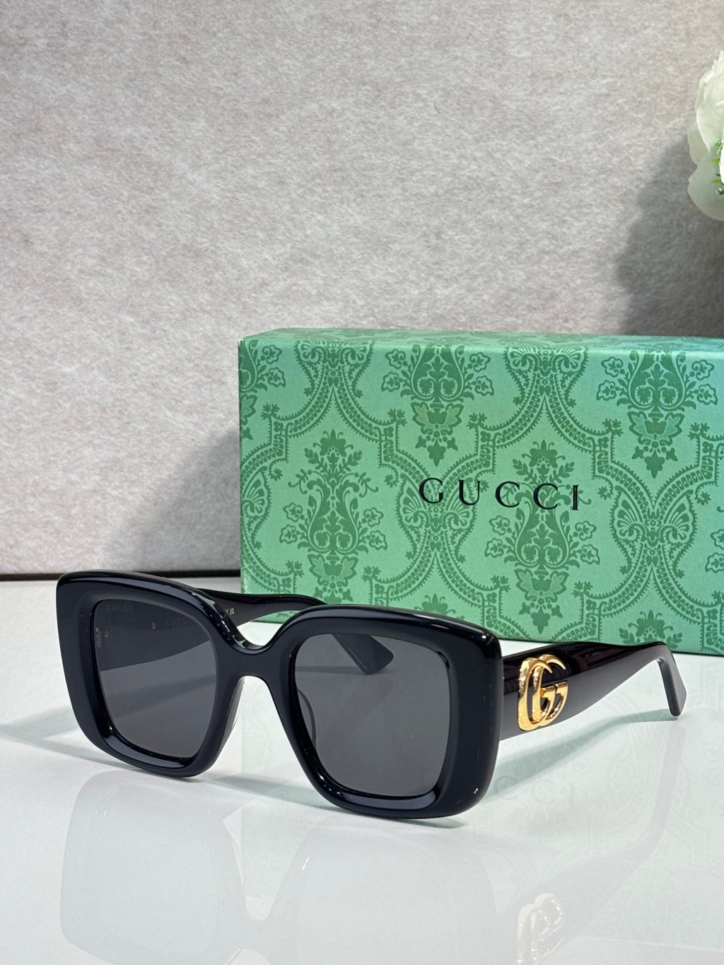 Gucci square sunglasses with black frames, tinted lenses, and gold GG temple detail