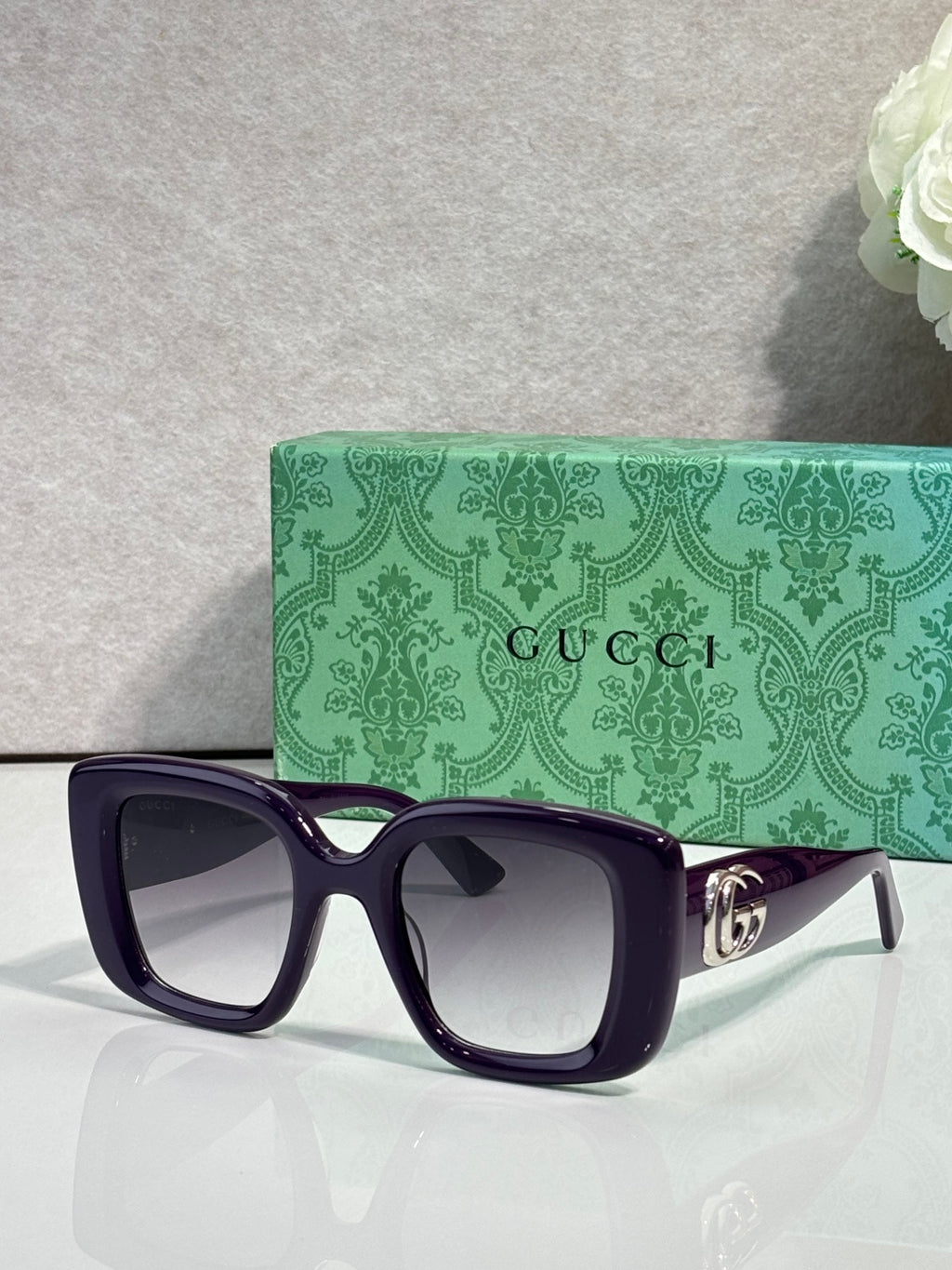 Gucci square sunglasses with dark frames and tinted lenses, gold GG logo on temple