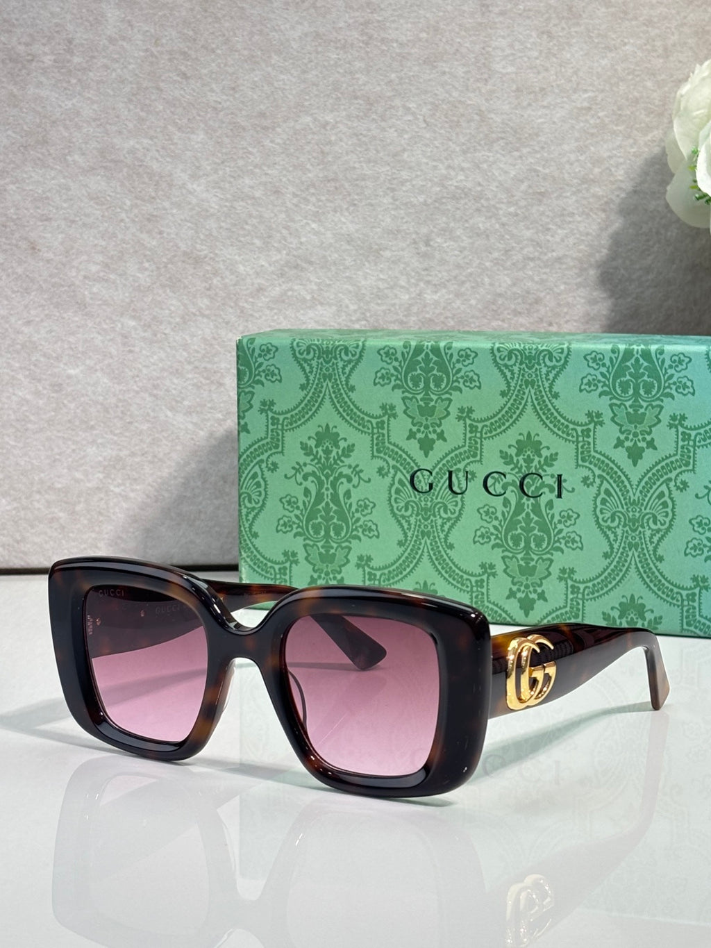 Gucci square sunglasses with pink-tinted frames and tinted lenses, gold GG temple detail