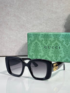 Gucci square sunglasses with matte dark frames and tinted lenses, gold GG temple detail