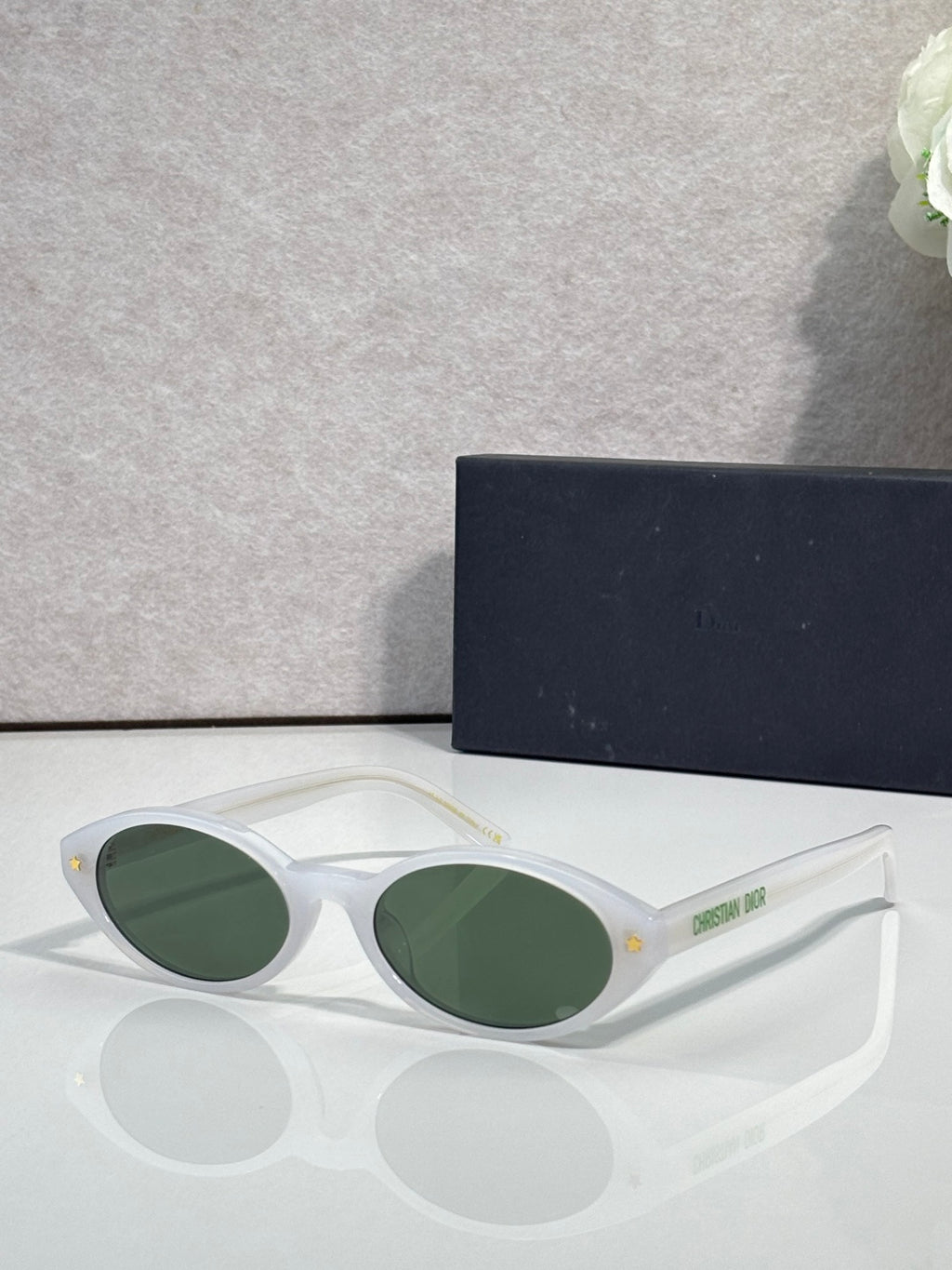 White Dior glasses with green round lenses and star detail on temple