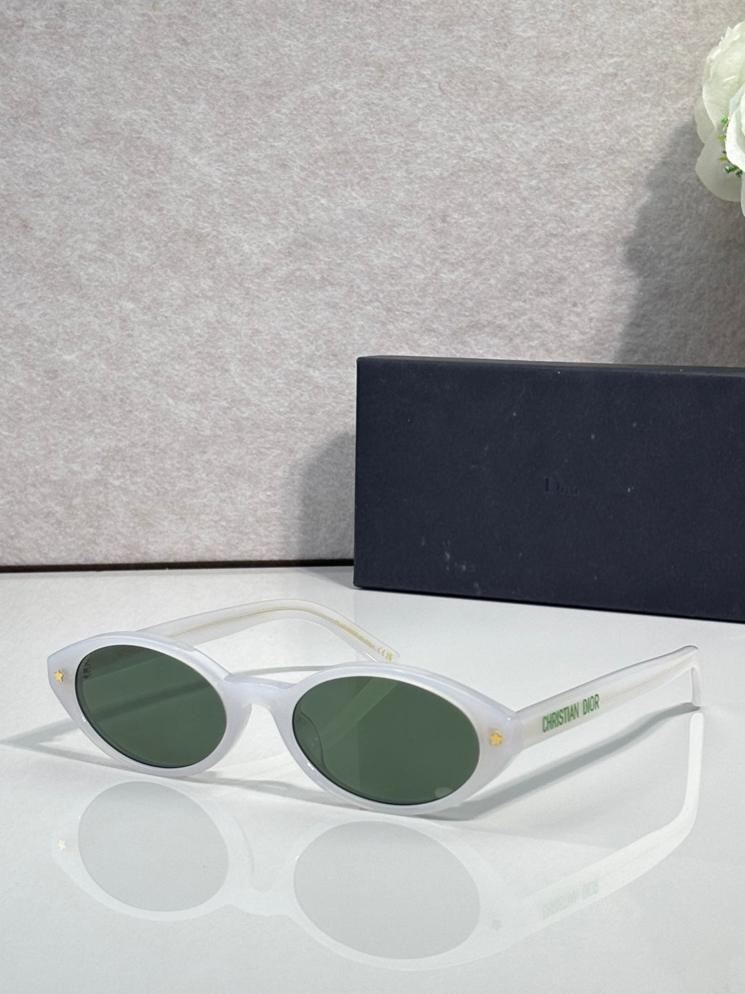 White Dior glasses with green round lenses and star detail on temple